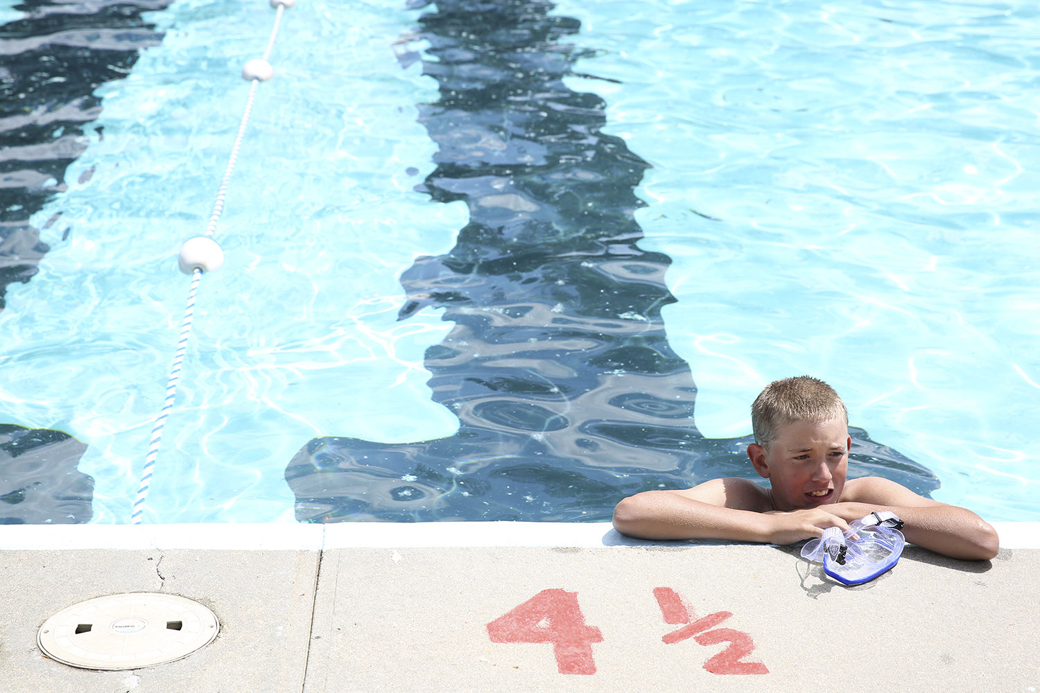 Quincy Ochs, 12, shivers holding onto the edge of the pool